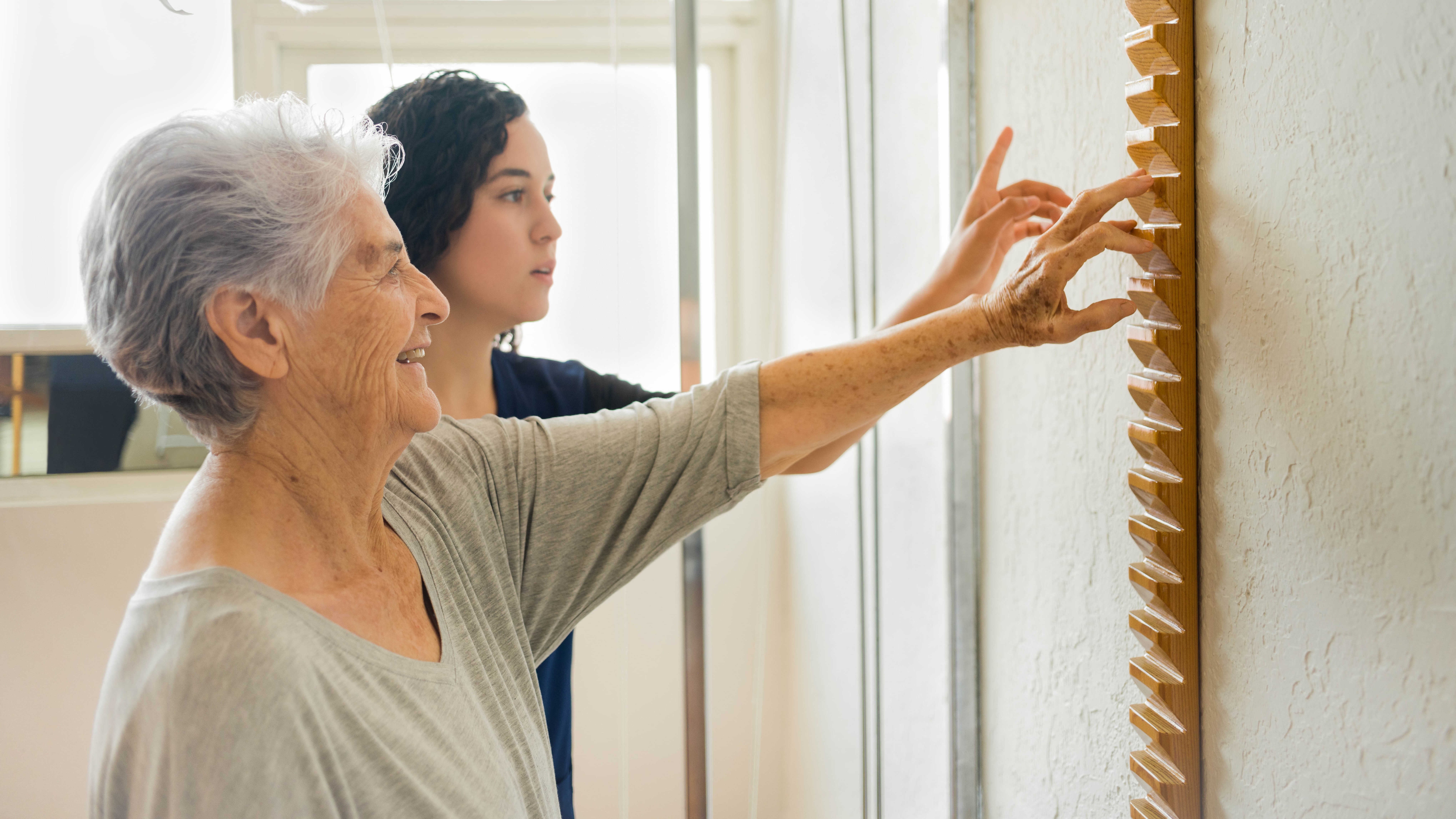Ergotherapeutin und Seniorin arbeiten an Fingerbewegungen