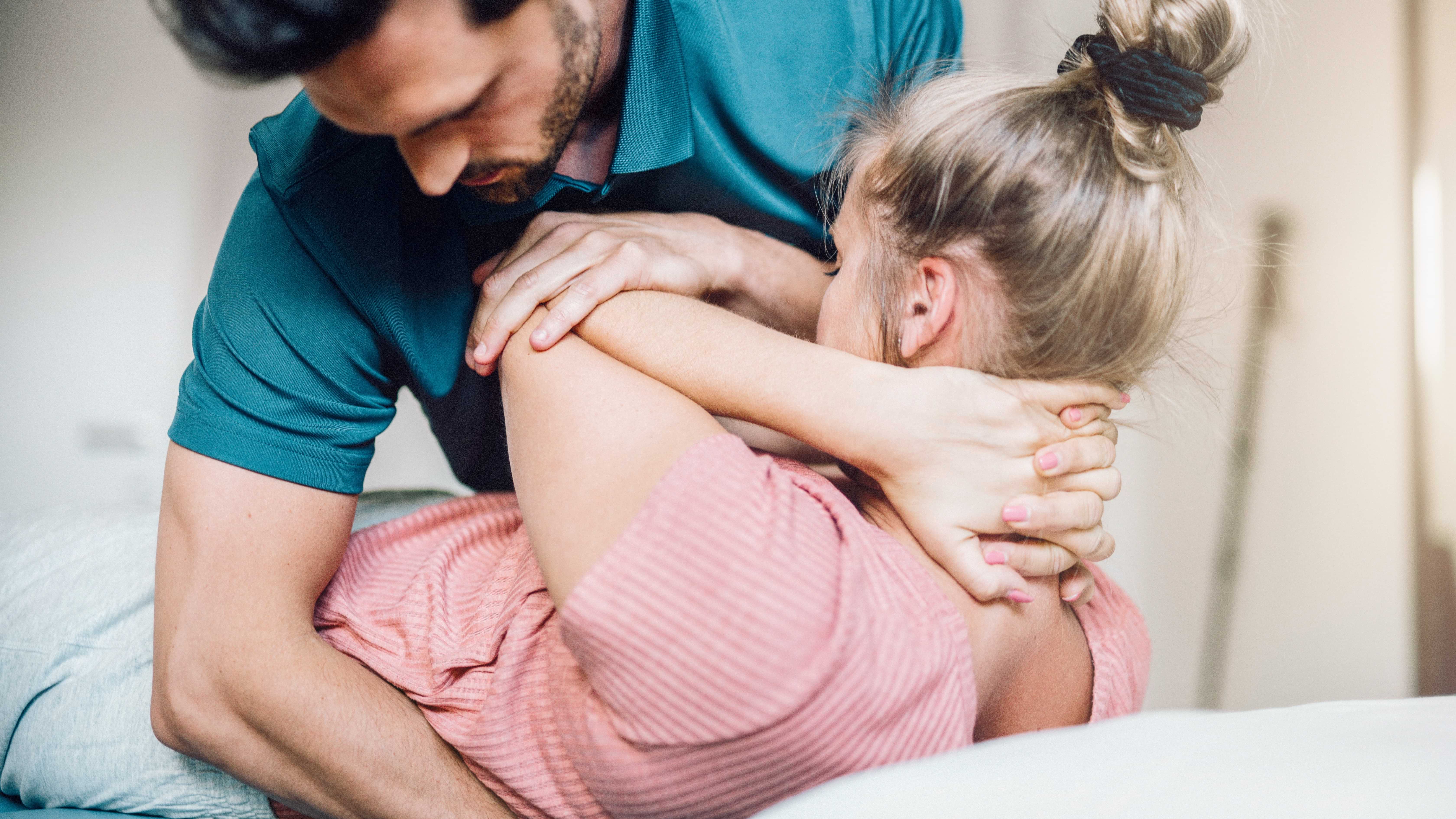 Physiotherapeut behandelt eine blonde Frau am Rücken