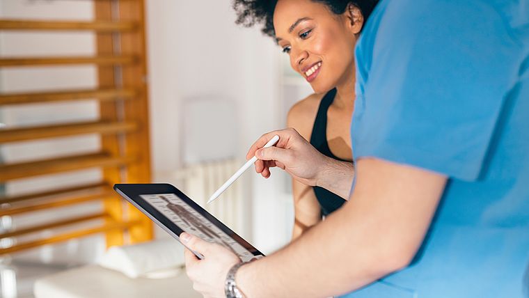 Therapeut dokumentiert gemeinsam mit Patientin auf Tablet