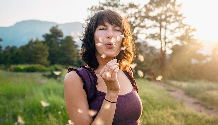 selbstbestimmte junge Frau mit Pusteblume freut sich über das Selbstbestimmungsgesetz