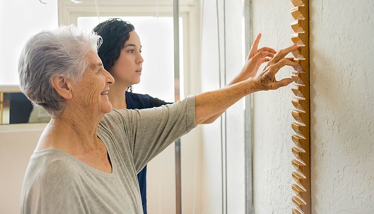 Ergotherapeutin und Seniorin arbeiten an Fingerbewegungen