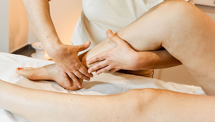 Physiotherapeut führt Manuelle Lymphdrainage an einer Wade durch