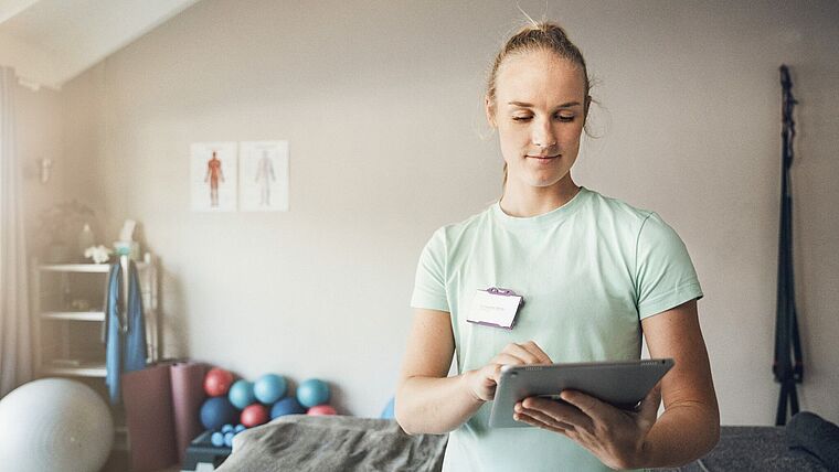Therapeutin in einer Pyhsiotherapiepraxis bedient ein Tablet