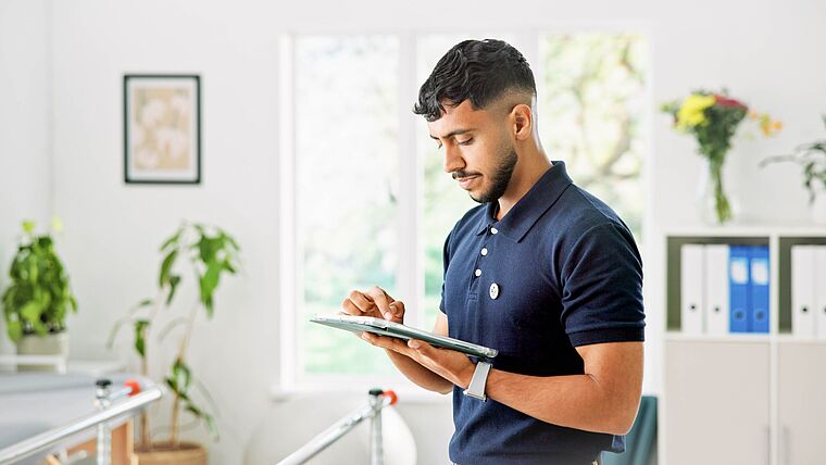 Physiotherapeut im Behandlungstraum tippt auf seinem Tablet