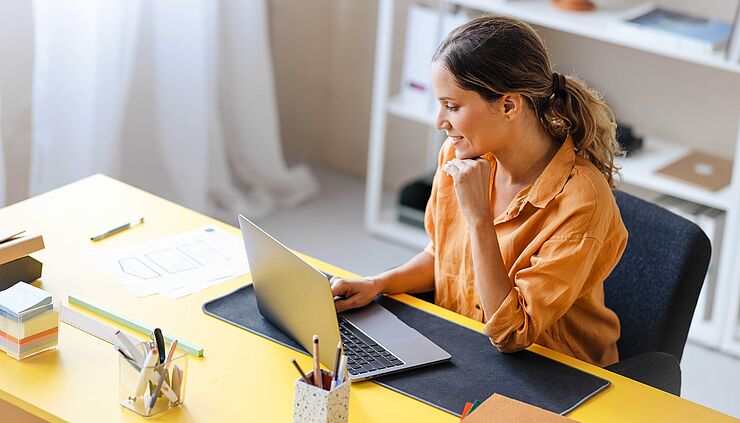 Frau arbeitet im Büro am Laptop möglichweise an der Mitarbeiterverwaltung 