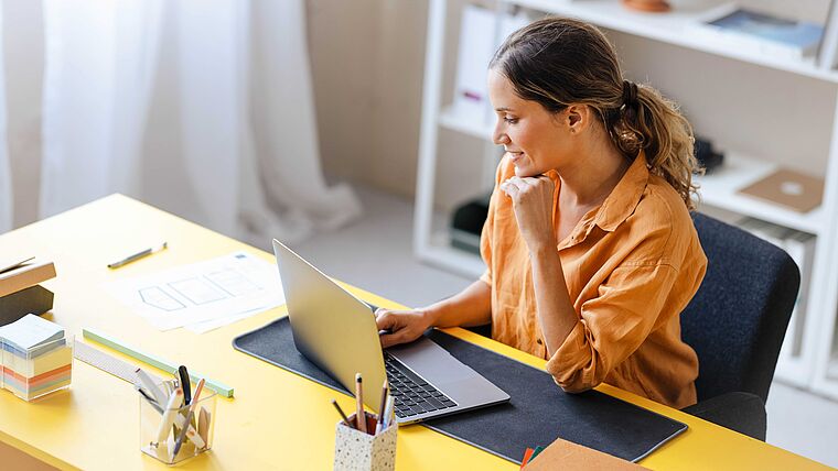 Frau arbeitet im Büro am Laptop möglichweise an der Mitarbeiterverwaltung 
