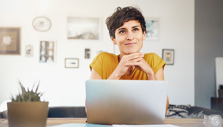 Junge Frau sitzt nachdenklich am Laptop