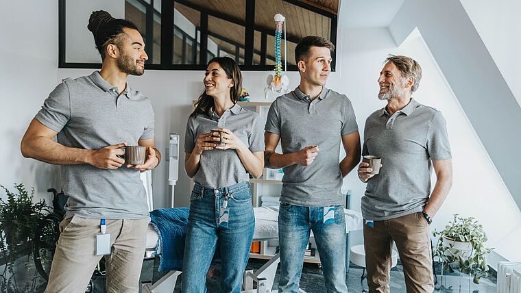 Team aus Physiotherapeuten trinkt Kaffee in einem Behandlungsraum