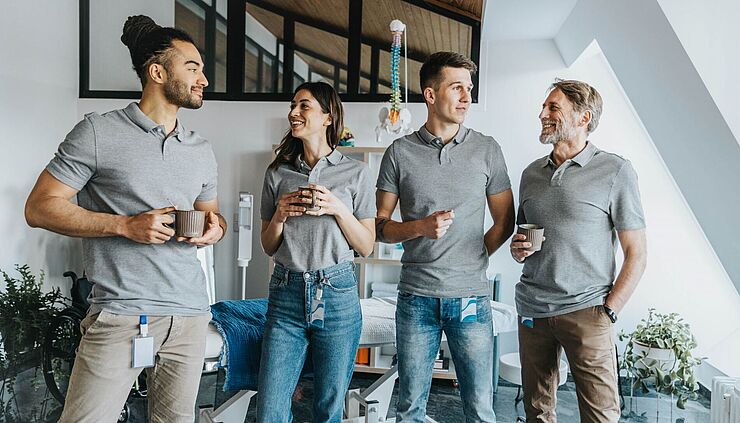 Team aus Physiotherapeuten trinkt Kaffee in einem Behandlungsraum