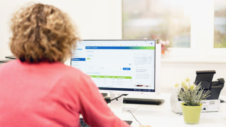 Frau sitzt vor Computer und hat Kundenportal MeinOptica offen