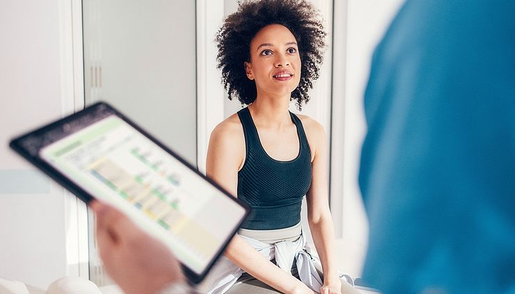 Patientin im Gespräch mit einem Therapeuten mit Tablet