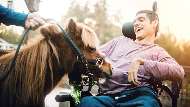 Junge mit Behinderung streichelt Pony