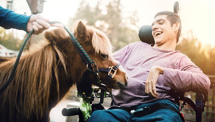 Junge mit Behinderung streichelt Pony