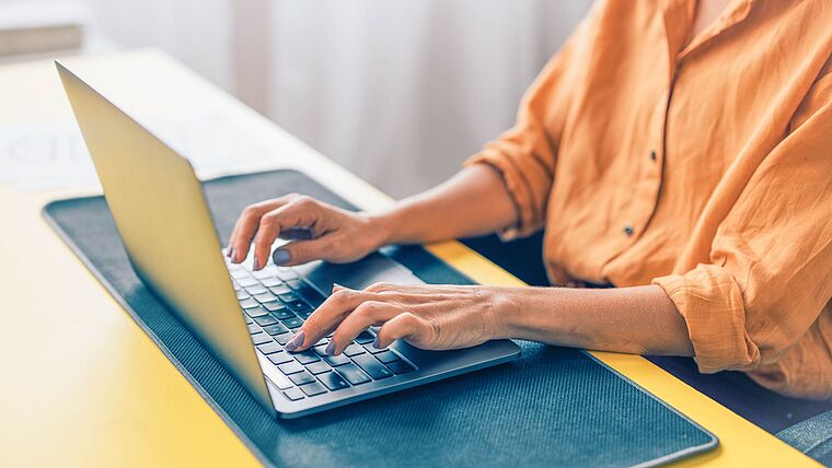 Nahaufnahme: Frauenhände tippen auf einem Laptop