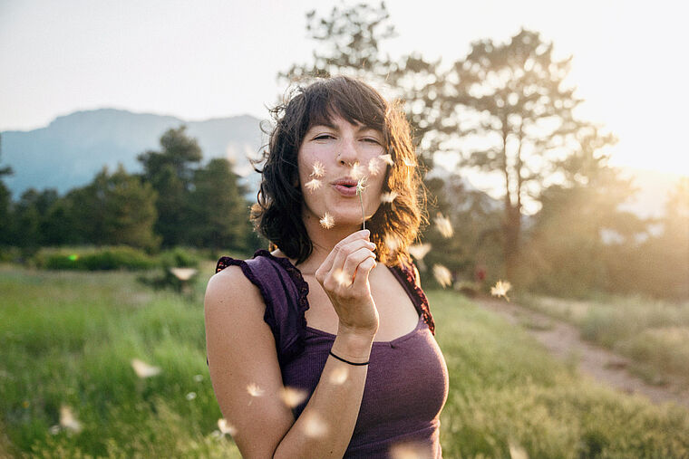 Junge Frau mit Pusteblume