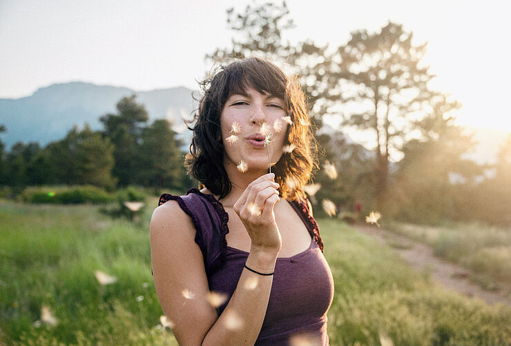 Junge Frau mit Pusteblume