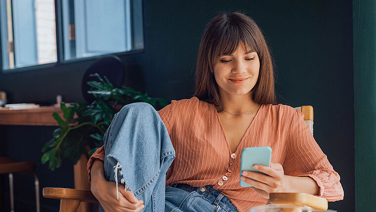 Junge Frau liest Nachrichten auf ihrem Smartphone