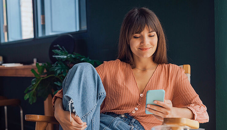 Junge Frau liest Nachrichten auf ihrem Smartphone