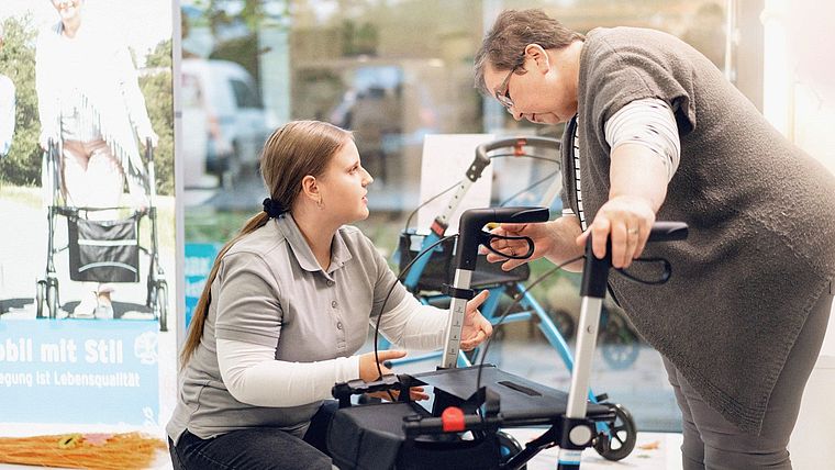Sanitätshausmitarbeiterin berät eine Kundin zu einem Rollator
