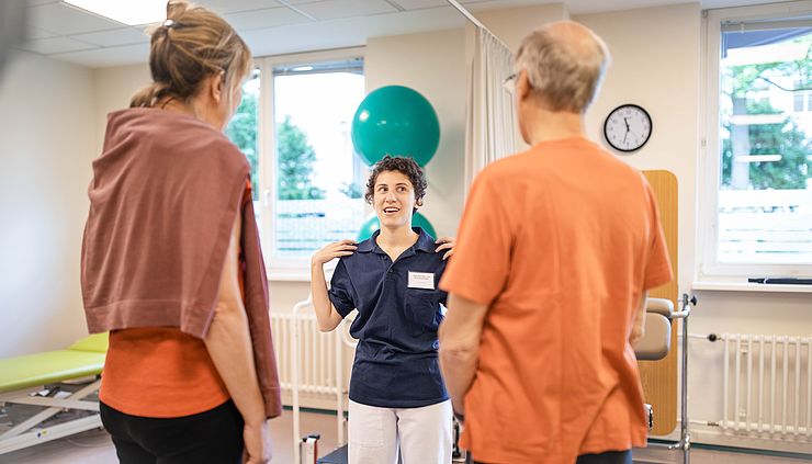 Physiotherapeutin erklärt zwei Patienten eine Übung