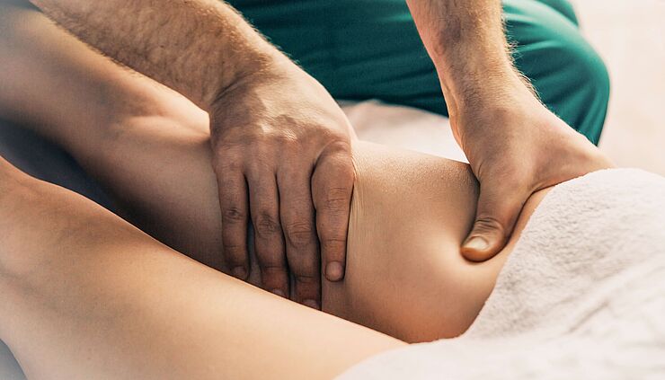 Physiotherapeut führt eine manuelle Lympdrainage an einem Bein durch