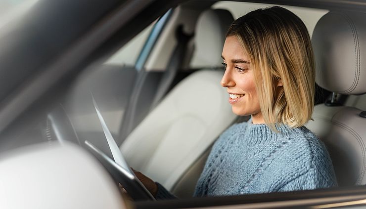 Junge Frau im Auto überprüft Termine auf dem Tablet
