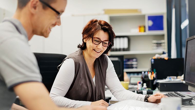 Ältere Frau und jüngerer Mann besprechen Papierkram