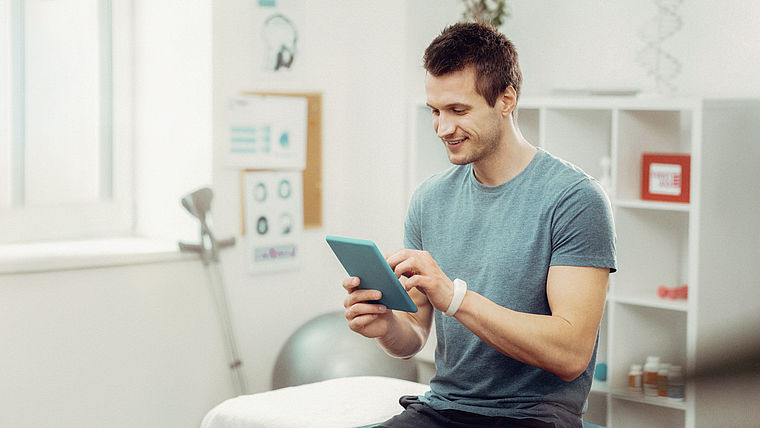 therapeut im Behandlungszimmer tippt auf Tablet