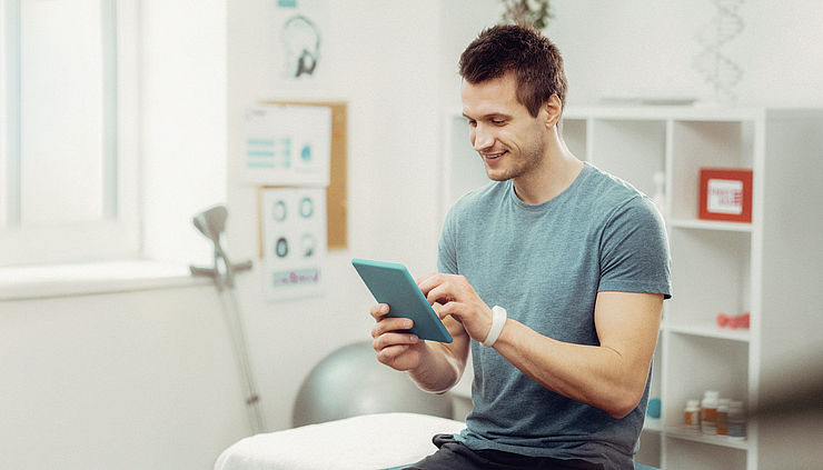therapeut im Behandlungszimmer tippt auf Tablet