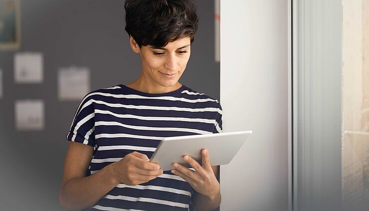 Junge Frau mit Tablet recherchiert Förderprogramme zur Digitalisierung im Gesundheitswesen im